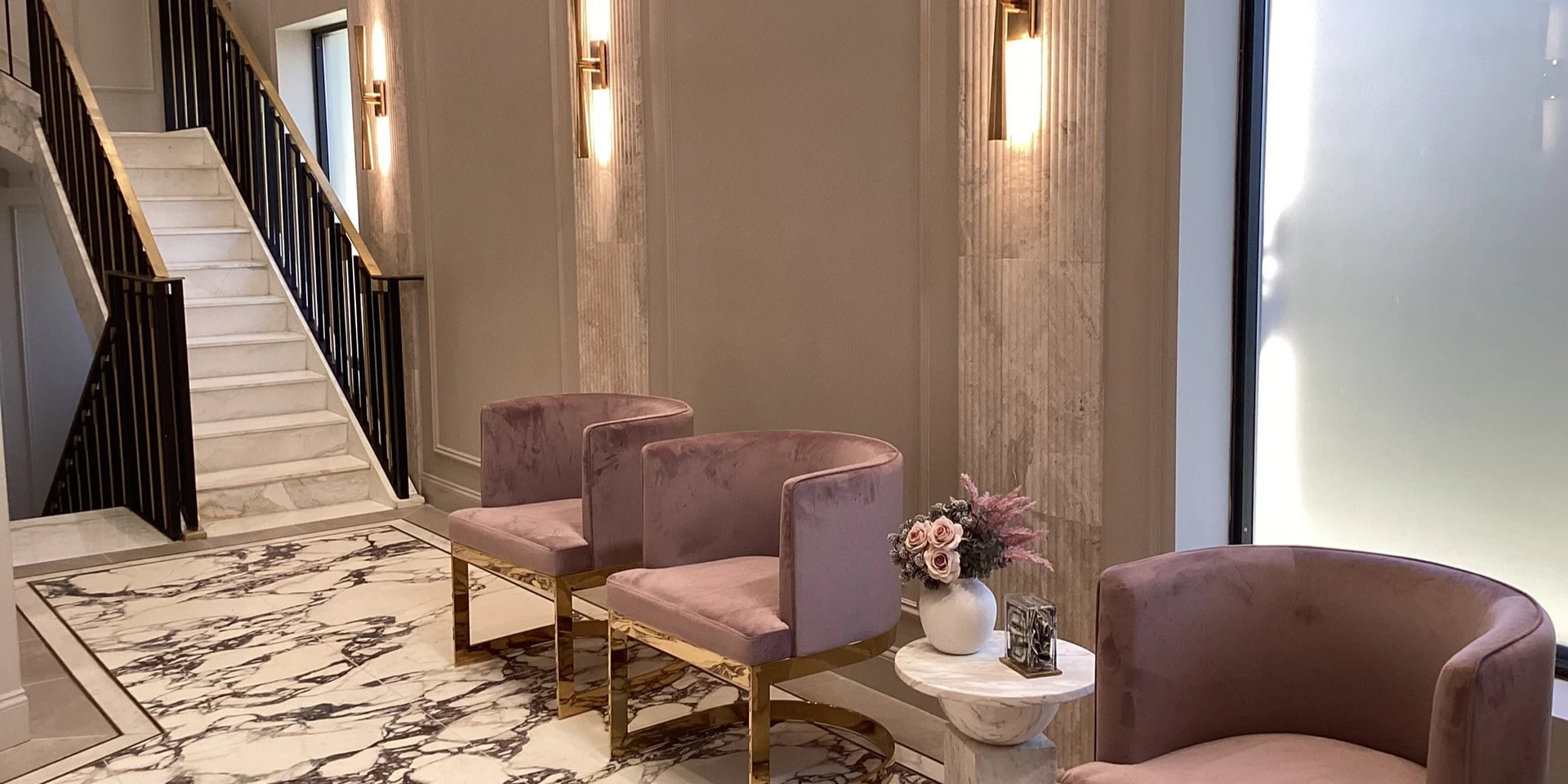 The lobby lounge, velvet armchairs beneath brass sconces