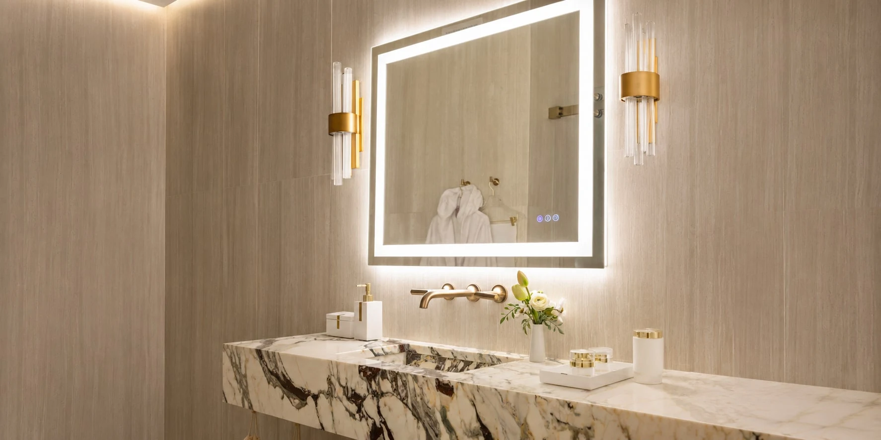 A preparation room vanity, lit mirror and waiting robes